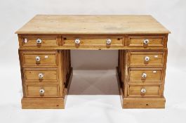 Pine twin-pedestal desk, the rectangular top over an arrangement of nine drawers, raised on a plinth