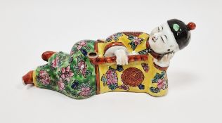 Chinese porcelain figure of reclining opium smoker painted in enamel, 19cm long