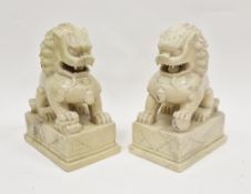 Pair of large Chinese carved soapstone models of lion dogs, each seated with front paw on a brocaded