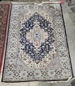 Pakistani blue ground wool rug, with central geometric medallion on floral field and floral