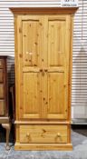Modern pine wardrobe, the two doors opening to a hanging space with draw below raised on a plinth