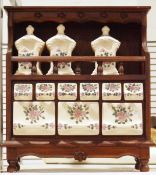 Vintage ceramic spice and herb cabinet with carved wooden frame supported by four bun feet,