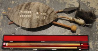 African souvenir shield in deer hide, with a spear knobkerry and fly switch and a cased pool cue