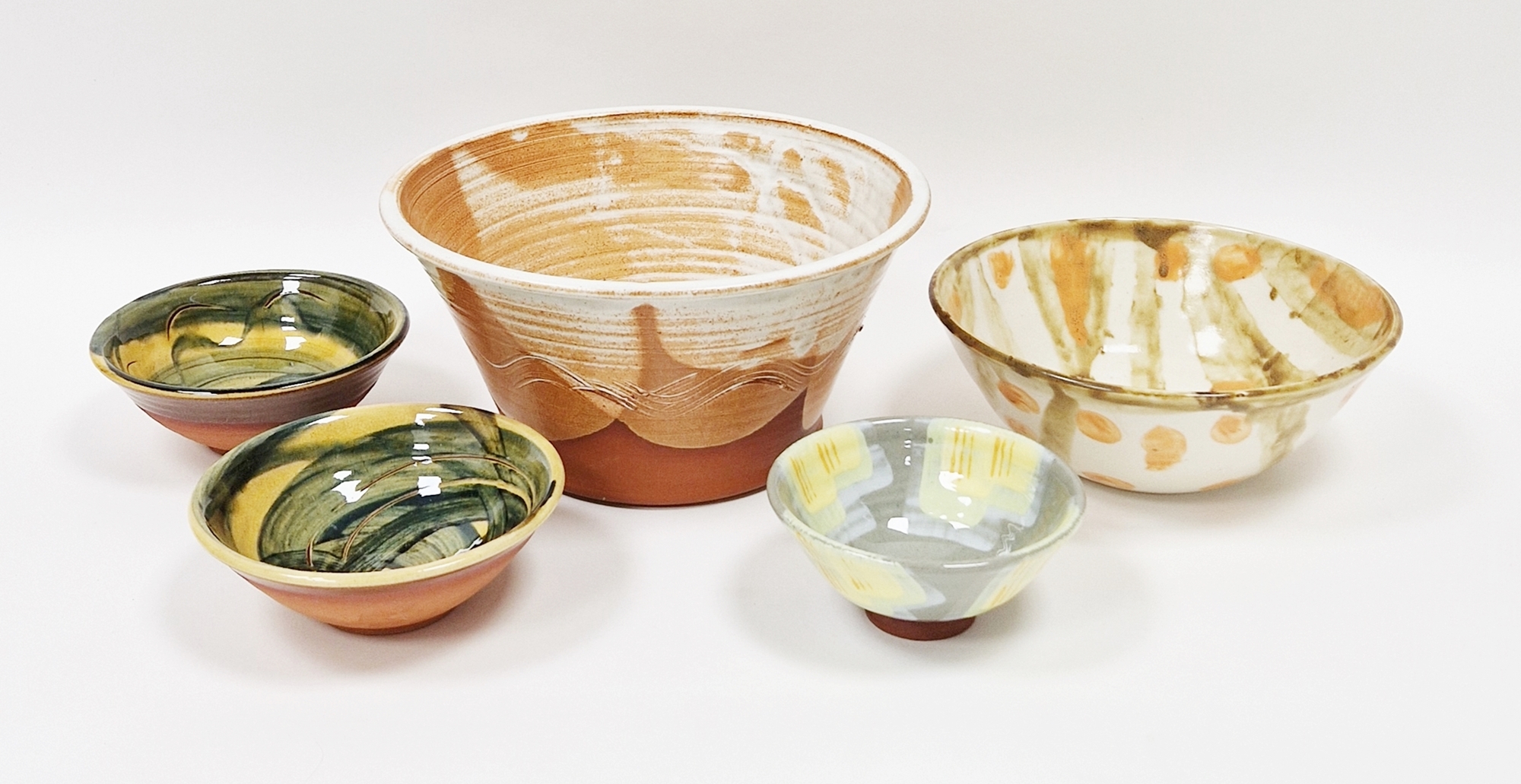 Five studio pottery bowls to include a pair by St. Fagans with blue swirls on yellow ground,