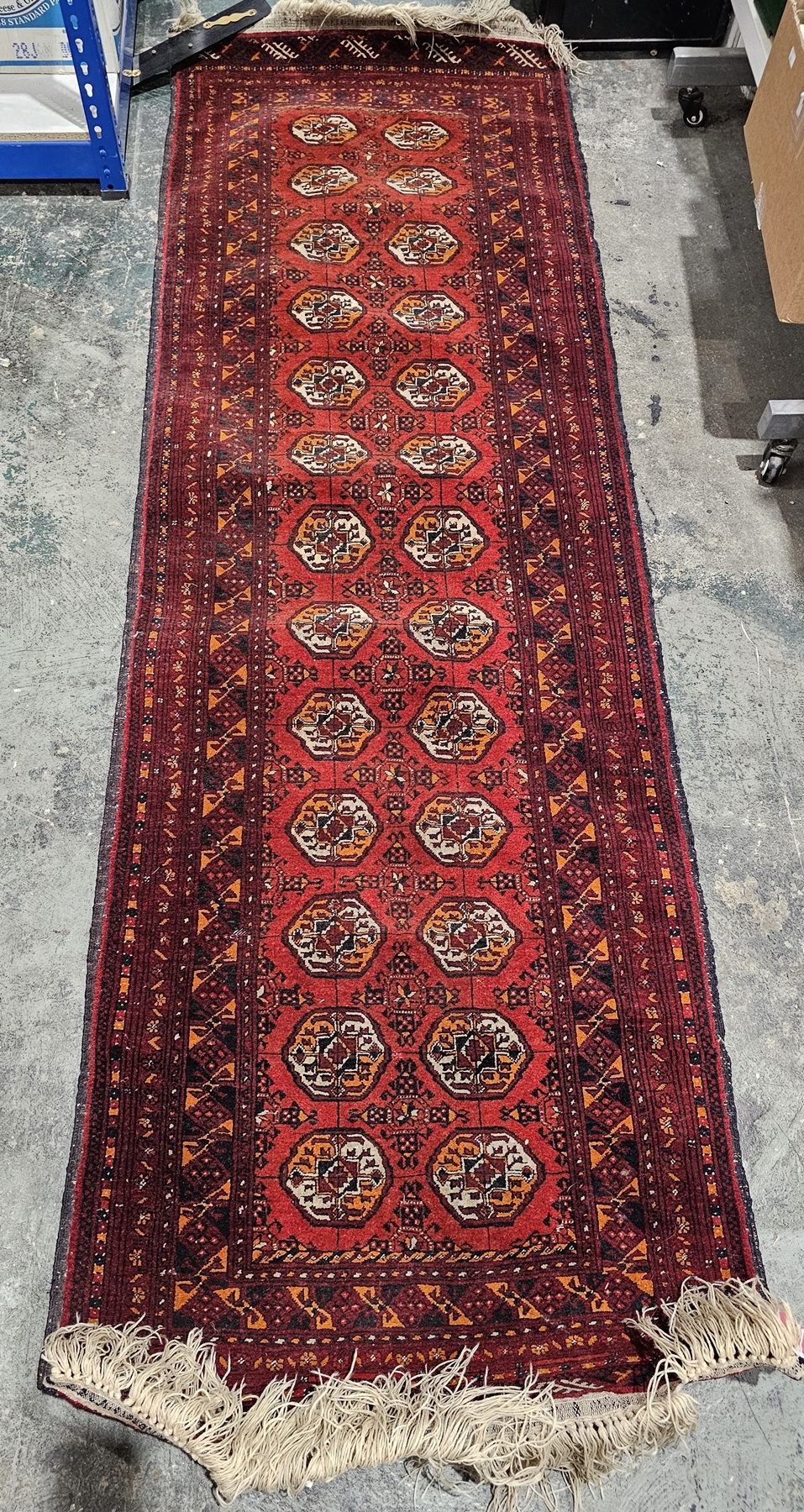 Persian red ground runner with two rows of thirteen elephant foot guls on geometric shaped field,