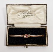 Early 20th century 9ct gold brooch, the plain scrolling bar collet set with a round mixed cut pink