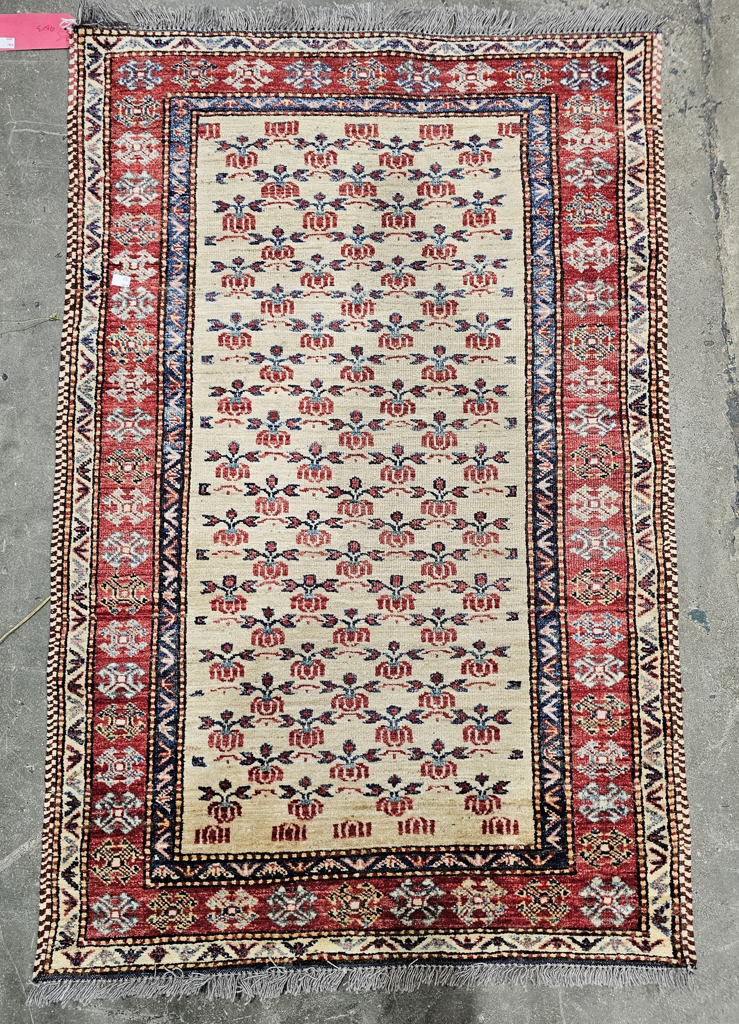 Eastern wool rug with allover stylised flowers to the cream field, red and blue geometric borders,