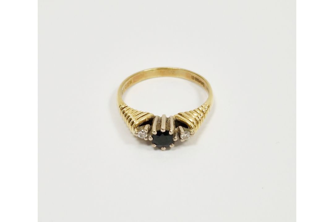 18ct yellow gold three-stone ring with a central claw set round sapphire flanked either side by