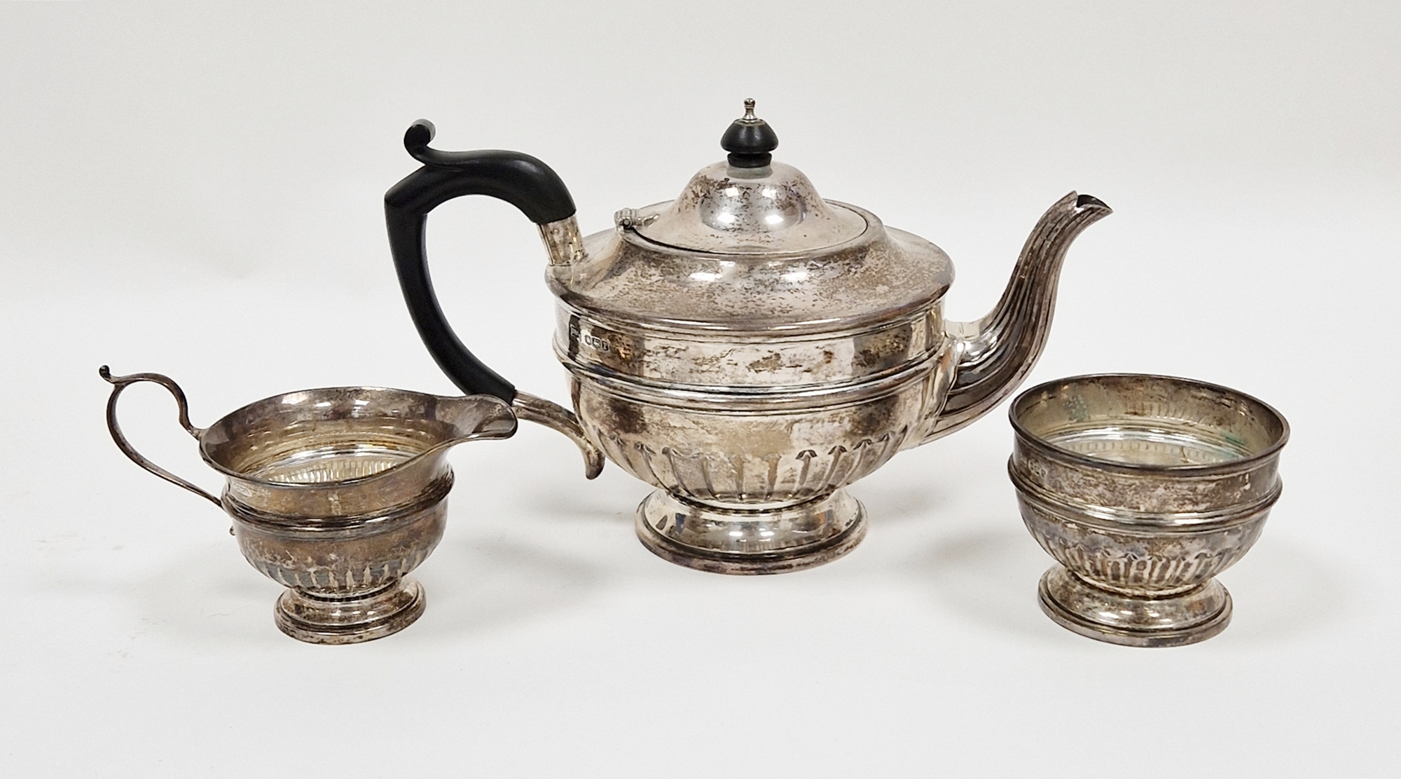 Silver three piece tea service, Sheffield 1933 and 1934, Walker & Hall, comprising teapot with ebony