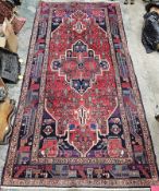 Iranian red ground carpet with large central geometric medallion on stylised geometric field,