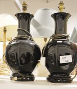 Pair of black ceramic baluster form table lamps, on Chinese style wooden carved bases, a squat