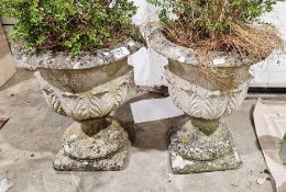 Pair of reconstituted stone garden urns with acanthus leaf design, on square pedestal base, 63cm