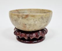Chinese soapstone bowl, of cup-form, raised on four stilt feet, on wooden stand 13cm diam.
