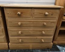 Modern pine chest of two short over three long drawers with turned pine handles and raised on a