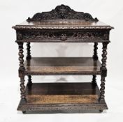 Late 19th/early 20th century oak three-tier buffet, the shaped back stand carved with a green man