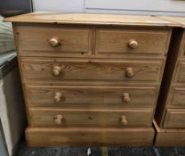 Modern pine chest of two short over three long drawers with turned pine handles and raised on a