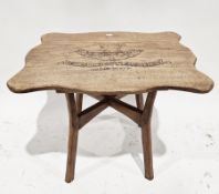 Mid-century oak handmade table, the shaped top carved with a military motif for the