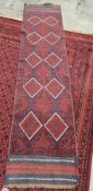 Eastern woollen red ground runner decorated with a geometric pattern of diamonds within a border,