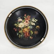 Black and gilt circular toleware tray, the pierced gallery with two carrying handles, hand decorated