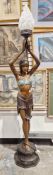 Cast bronze standard lamp in the form of a 1920's dancing girl holding a glass flame torch above her