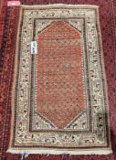 Iranian old handknotted rug with centre red background with multi-coloured designs in creams,