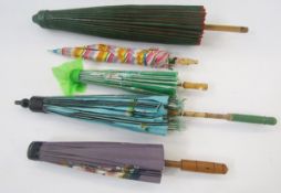 Four various paper parasols and a child's umbrella, the wooden handle of the child's umbrella carved