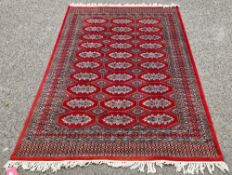 Persian rug with red ground with three rows of 10 geometric medallions in grey, red, gold and