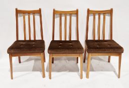 Set of three mid-century teak dining chairs with slat backs and brown buttoned upholstered seats,