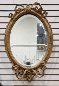 19th century giltwood and gesso oval girandole mirror, the frame with foliate scroll cresting and
