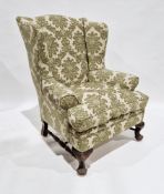Large wing back armchair in the George III manner, with cream and green floral upholstery and raised