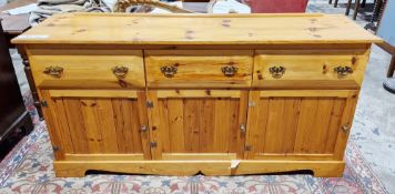 Modern pine dresser base with three deep drawers and three cupboard doors, raised on bracket feet,