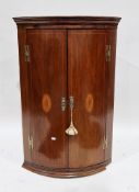 George III mahogany inlaid bowfronted hanging corner cabinet, the two panel doors with inlaid patera