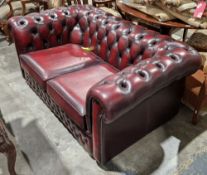 Victorian-style Chesterfield two-seater sofa upholstered in oxblood red button back leather with two