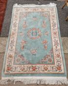 Chinese wool rug in green ground with floral design in blue, mauve, pink, salmon and floral