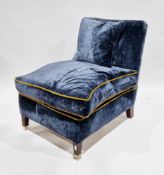 Modern easy chair upholstered in blue velvet type fabric, with gold coloured trim, raised on front