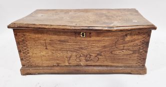 Early 19th century elm blanket box, the hinged lid opening to an empty space, the front panel carved