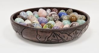 Large turned carved wooden bowl containing over 50 carved gemstone eggs including tiger's eye,