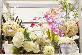 A quantity of faux floral arrangements most contained within ceramic or glass planters to include