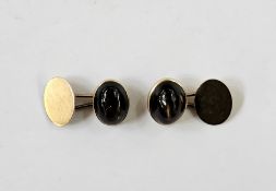 Pair of gold-coloured cufflinks, each set with an oval brown stone cabochon displaying Chatoyancy