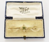 Edwardian gold bar brooch set with a central circular peridot surrounded by clusters of seed pearls,
