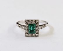 White metal, diamond and emerald ring, the central cut emerald within a border of 14 brilliant cut