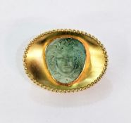 Gold-coloured metal and turquoise brooch, oval with beaded border, the central turquoise carved with