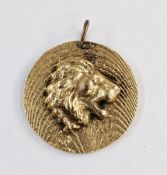 Yellow metal pendant of circular form, modelled with a lion's head on a textured ground, unmarked (