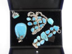 Silver coloured metal turquoise set pendant on heavy oval link chain, the pendant with multiple