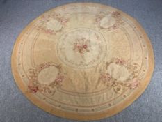 A hand woven Aubusson style rug with floral spray medallions on a beige ground. Dia.240cm.