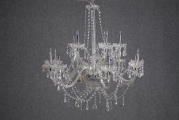 A crystal chandelier with eleven branches of lights. H.70cm. (In need of some repair).