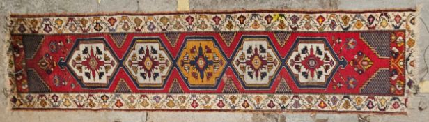 A Talish runner with repeating medallions on a burgundy ground. H.380 W.75cm.