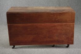 A 19th century oak drop flap dining table on tapering square supports terminating in brass cup