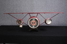 A wall mounted clock. The clock face in the style of aircraft instrument dials. H.40 W.124cm.