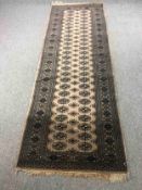 A Bokhara style runner with repeating gul medallions on an ivory ground. L.264 W.94cm.